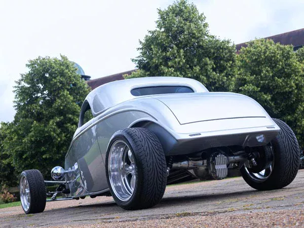 Rear three-quarter view of the silver Ford Model B hot rod showing its chrome wheels
