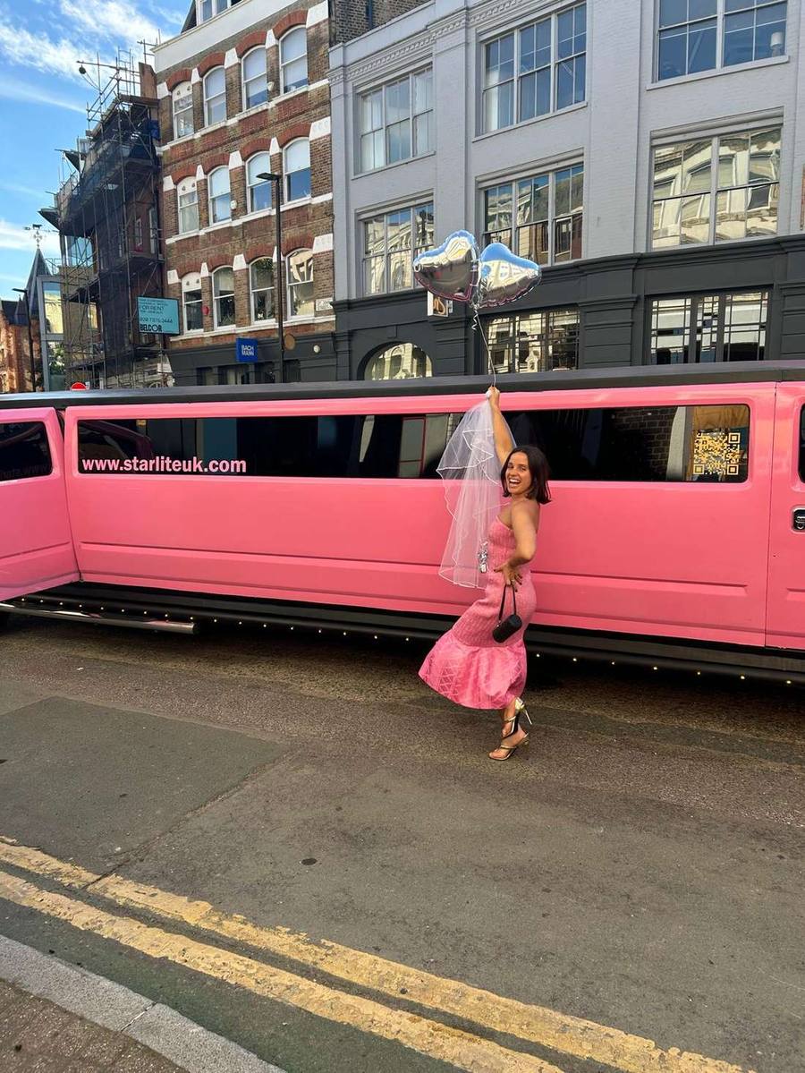 Bride to be with balloons standing in front of the pink Hummer H2 stretch limousine