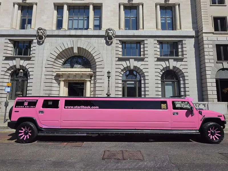 Pink Hummer H2 stretch limousine, registration P23 HUM, parked outside a stone building