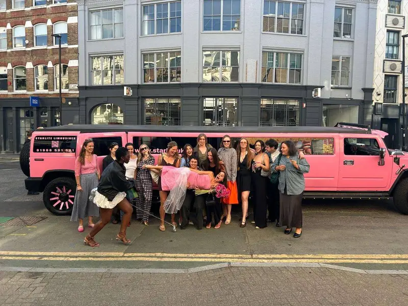 Hen party group posing beside the pink Hummer H2 stretch limousine